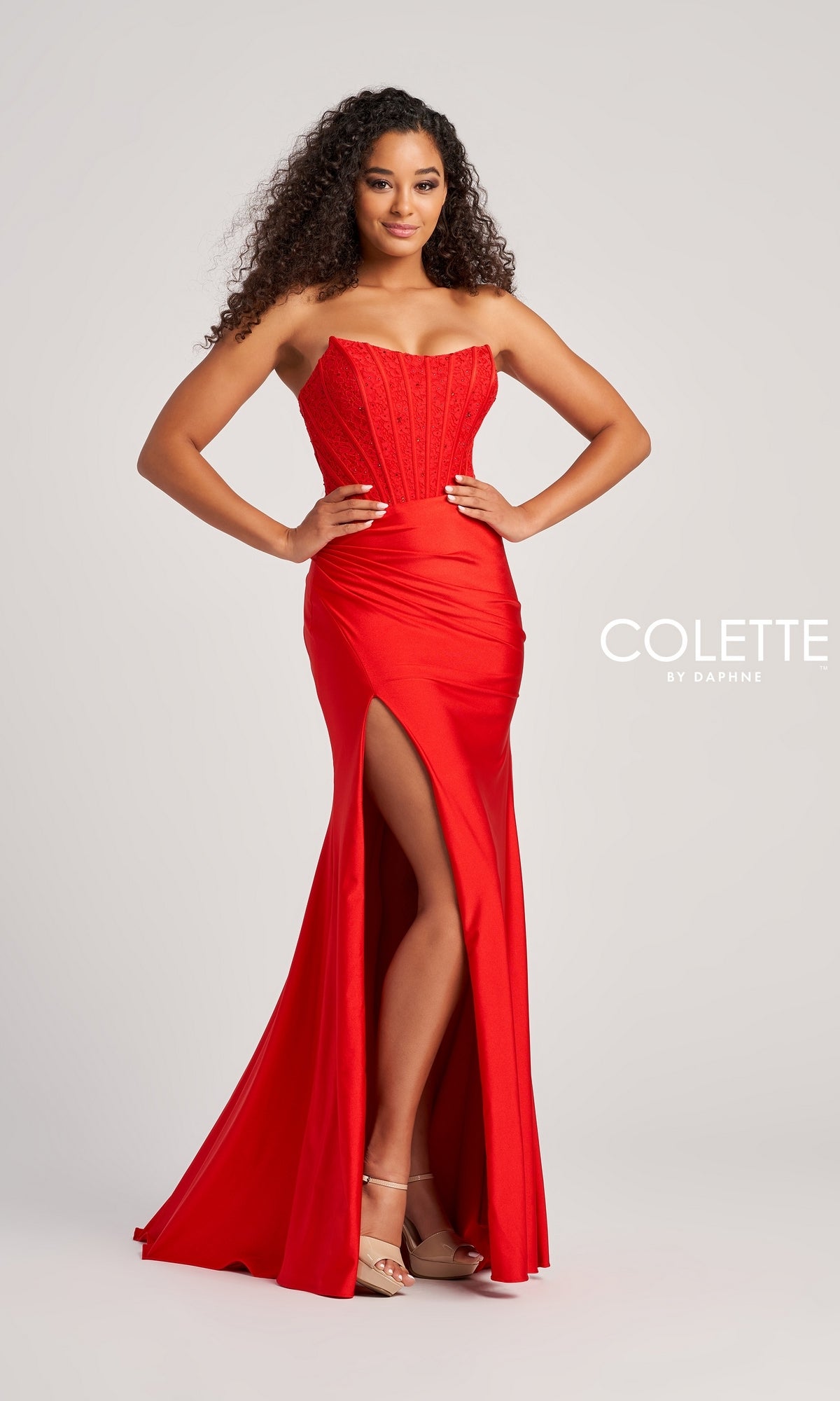 A woman poses against a light gray background in the Strapless Colette Long Designer Prom Dress CL5158, a form-fitting red gown with a high slit. The text